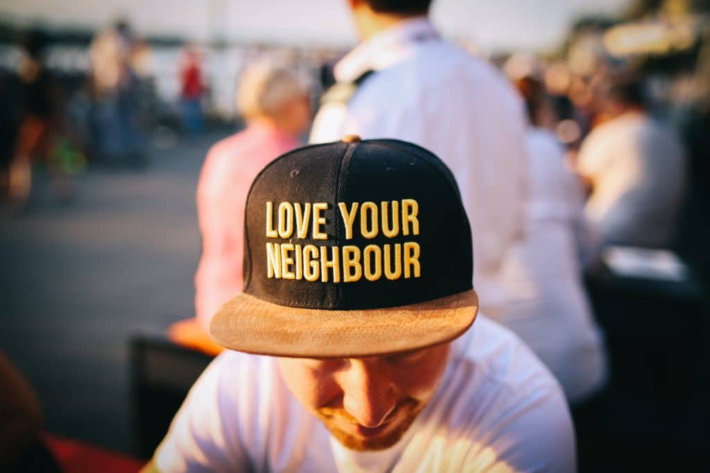 Homme avec casquette sur laquelle est écrit love your neighbour
